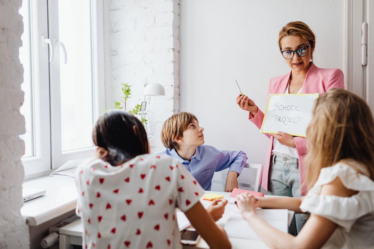 A teacher engaging with students in a classroom setting for a school project discussion.